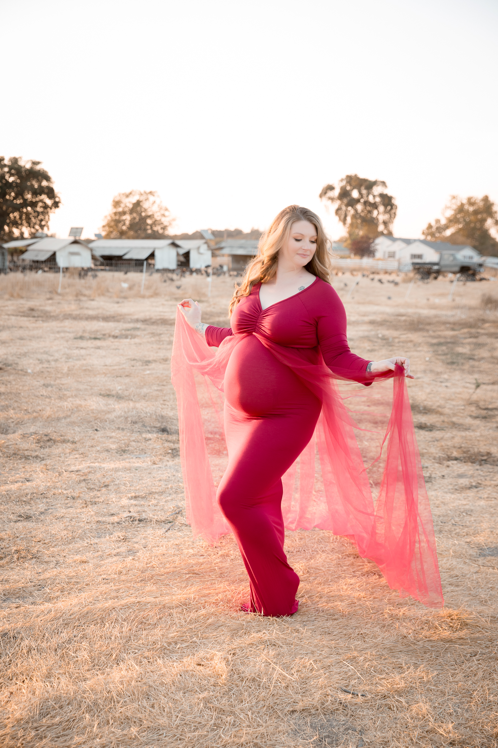 pregnant woman in red gown in grass