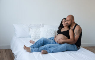 couple sitting on bed embracing pregnancy